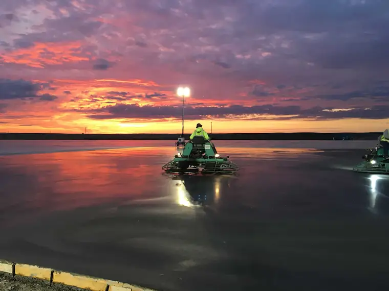 A ride-on power trowel finishing the Autozone slab in Pasco under a red sunset