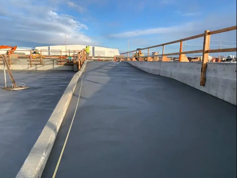 A freshly placed sloped concrete floor between formed walls on a Fisher expansion project