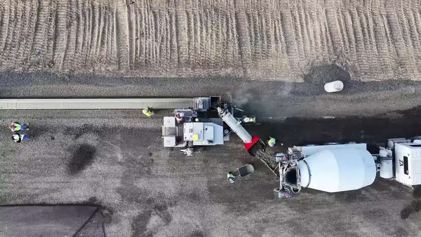 Aerial view of a Poppoff Power Curber extruding curb while a mixer feeds it