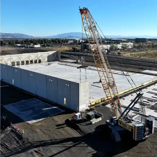A crawler crane lifting concrete tilt-up wall panels, seen from above