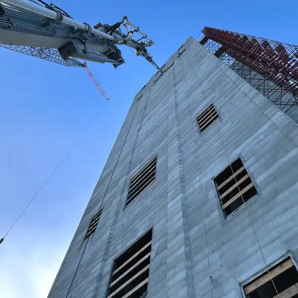 Looking up the concrete wall of a grain tower with a boom reaching over it